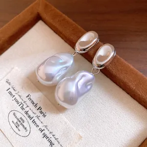 Detailed macro view of French vintage Baroque pearl pea earrings on cream display fabric