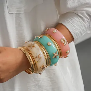 Detail shot of ocean-themed resin bangles with starfish, shells, and faux pearls
