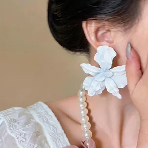Close-up detail of an elegant white spray-painted flower stud earring on a model ear