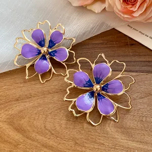 Close-up of elegant purple enamel flower earrings displayed on a rustic wood background