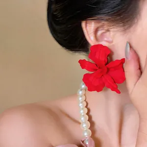 Macro detail of a stylish oversized red matte flower stud earring on an Asian model
