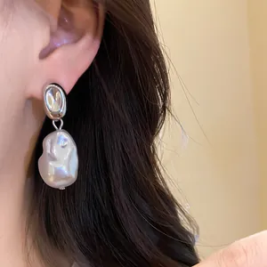 Close-up detail of a French vintage baroque pearl drop earring worn on a female ear