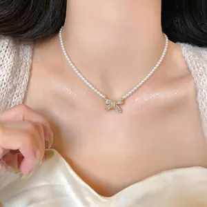 Detailed view of 18k gold plated pearl necklace with sparkling crystal bow pendant