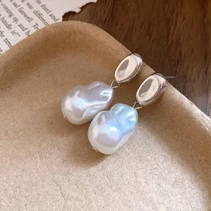 Detail view of French vintage silver pea-shaped pearl drop earrings on a rustic paper tray