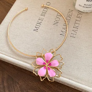 Macro detail of a high-end gold open choker with a delicate pink enamel flower pendant