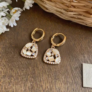 Detail of 18k gold plated drop earrings featuring sparkling cubic zirconia and opal stones.