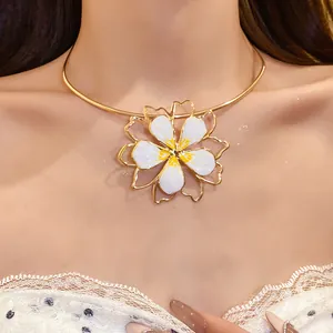 Close-up detail of a gold choker with a white enamel hollow flower pendant worn by a model