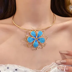 Detailed view of a blue enameled hollow flower pendant on a sleek gold choker chain.