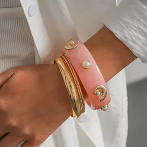 Detail shot of a 4-piece resort style set featuring pink resin and gold bangles