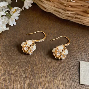 Close-up detail of 18k gold plated flower ball earrings with zircons and opal beads.