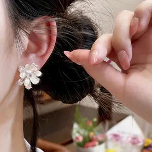 Boucle d'oreille fleur en argent avec détails en zircon scintillant sur l'oreille.