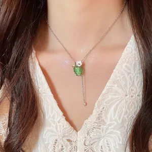 Elegante collana con ciondolo a forma di uva verde gelatina e piccolo fiore bianco.