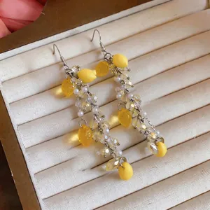 Elegant yellow resin lemon tassel earrings with pearls and crystals on jewelry tray