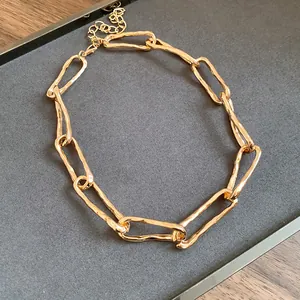 Vista dettagliata di una collana a catena a maglie ritorte dorate su un vassoio grigio