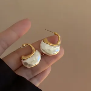Dettaglio ravvicinato di orecchini minimalisti a forma di C in oro e resina bianca