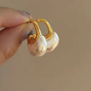 Vista dettagliata di eleganti orecchini a C dorati con pendenti in perla di resina