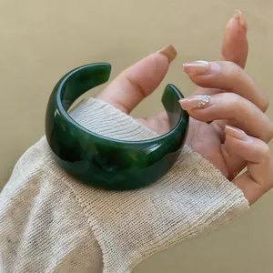 Detaillierte Nahaufnahme eines breiten, grün marmorierten Acryl-Armreifs am Handgelenk