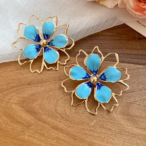 Close-up of blue enamel hollow flower stud earrings on a wooden background