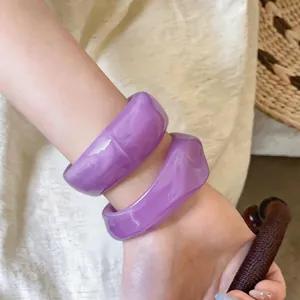 Nahaufnahme modischer lila Acryl-Armreifen mit unregelmäßiger Geometrie und Marmor-Effekt