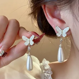 Elegante, 14K vergoldete Schmetterlingsohrringe mit Tropfenperle, an einem Model präsentiert