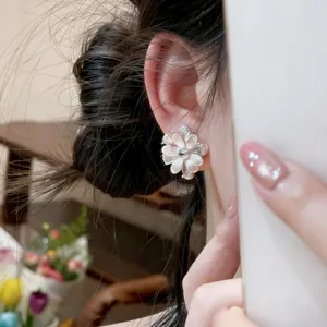 Detail shot of silver flower stud earring with micro-pave zirconia worn on ear