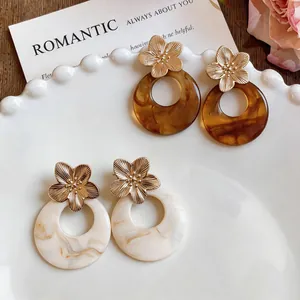 Close-up of vintage French resin hoop earrings with gold floral studs on a decorative plate
