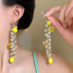 Detailed close-up of handmade lemon tassel earrings with sparkling crystals and pearls