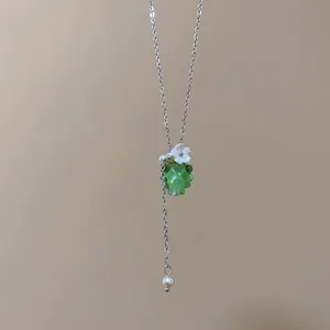 Primo piano della collana di uva verde gelatina con fiore bianco e dettagli in perle