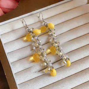 Close-up detail of yellow resin lemon tassel earrings with pearls and crystals