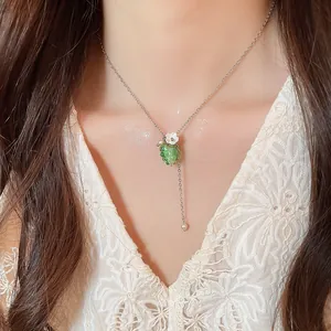 Dettaglio della collana con pendente a uva verde e fiore bianco indossata dal modello