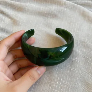Nahaufnahme eines marmorierten grünen Acryl-Armreifs mit unregelmäßigem Design.