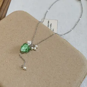 Vista dettagliata della collana con ciondolo a uva verde con perle e fiori bianchi piccoli