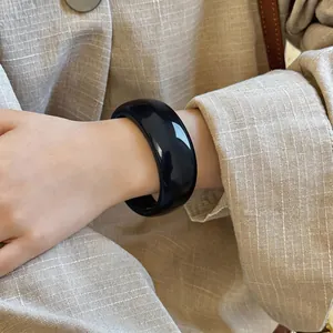 Nahaufnahme eines minimalistischen glänzend schwarzen Acryl-Armreifs am Handgelenk