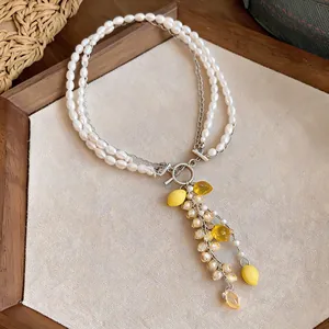 Detailed macro view of a double-strand pearl necklace with yellow lemon resin charms.
