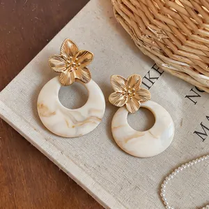 Detailed view of French vintage gold flower earrings with cream marble resin hoops