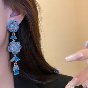 Exquisite close-up of vintage flower tassel earrings with blue stones on a model's ear