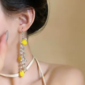 Elegant detail of lemon tassel earring featuring pearls and crystals on a model