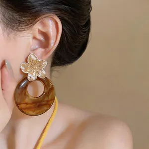 Detailed view of vintage style gold flower earrings featuring a brown marbled resin ring