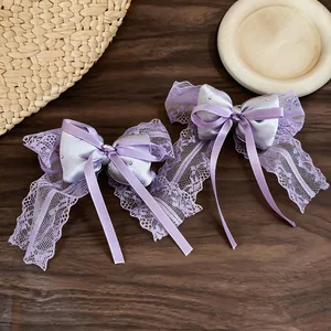 Detailed view of elegant purple lace bow hair clips with satin ribbons on a wooden surface