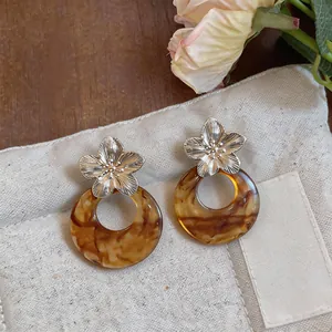 Detailed view of French vintage Maillard style resin flower hoop earrings on beige fabric