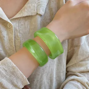 Nahaufnahme von lebhaften grünen marmorierten Acryl-Armreifen mit unregelmäßigem Design