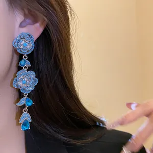 Detail view of exquisite vintage floral tassel earrings with blue zircons worn by a model