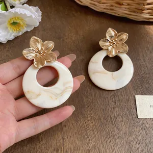 Close-up of French retro resin flower hoop earrings with golden floral details.