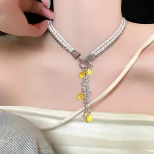 Close-up detail of pearl and crystal necklace with cute yellow resin lemon tassels