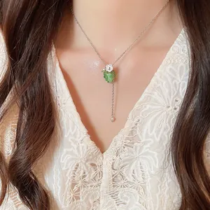 Dettaglio di una delicata collana con pendente a uva verde sulla clavicola