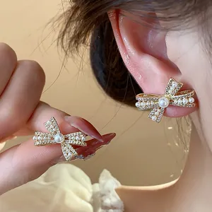 Nahaufnahme eleganter 14K vergoldeter Schleifenohrringe mit Perlen und Kristallen.