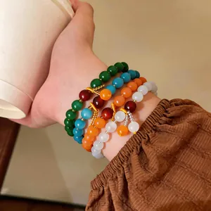 Vista dettagliata di braccialetti con perline occhio di gatto retrò colorati al polso.