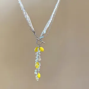 Detail of multi-layer pearl necklace with yellow lemon resin charms and crystal tassels