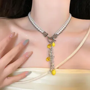 Close-up of pearl and crystal necklace with yellow resin lemon tassels for beach vacation.