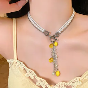 Detailed view of a layered pearl and resin lemon tassel necklace worn by a model